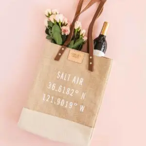 Chelsea Chatts Salt Air Wine Tote Bag filled with a bottle of wine and bouquet of roses