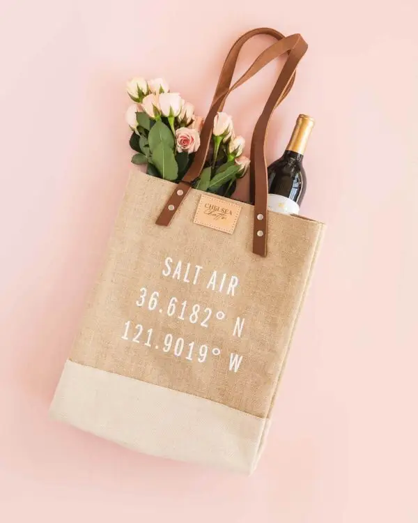 Chelsea Chatts Salt Air Wine Tote Bag filled with a bottle of wine and bouquet of roses