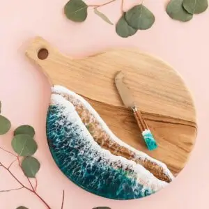 Ocean, River Inspired Charcuterie Board and Knife Set on pink background with eucalyptus leaves